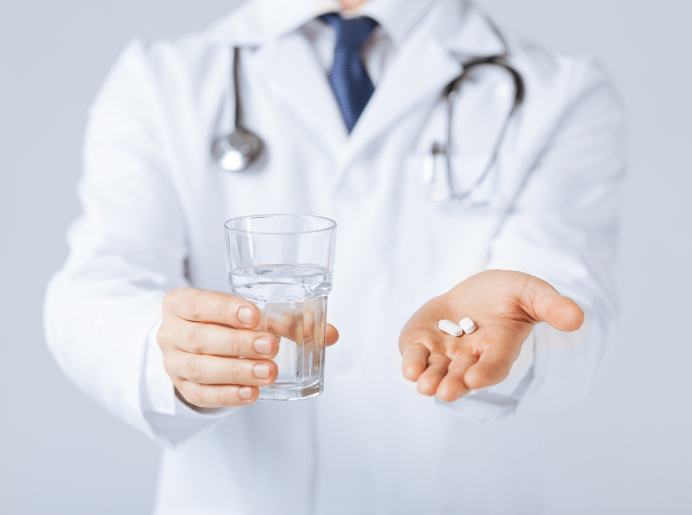 picture of doctor hands giving white pills and glass of water